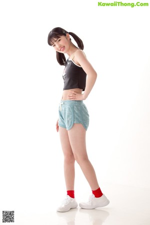 A woman in a black top and blue shorts posing for a picture.