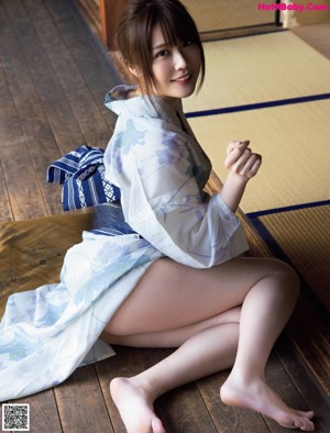 A woman sitting on a train platform next to a train station.