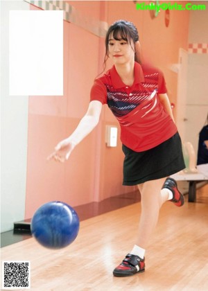 A couple of women standing next to each other holding bowling balls.