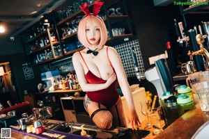 A woman in a red corset and fishnet stockings posing in a bar.