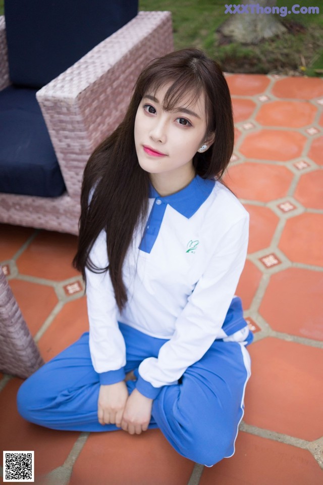 A woman in a white shirt and blue pants sitting on the ground.