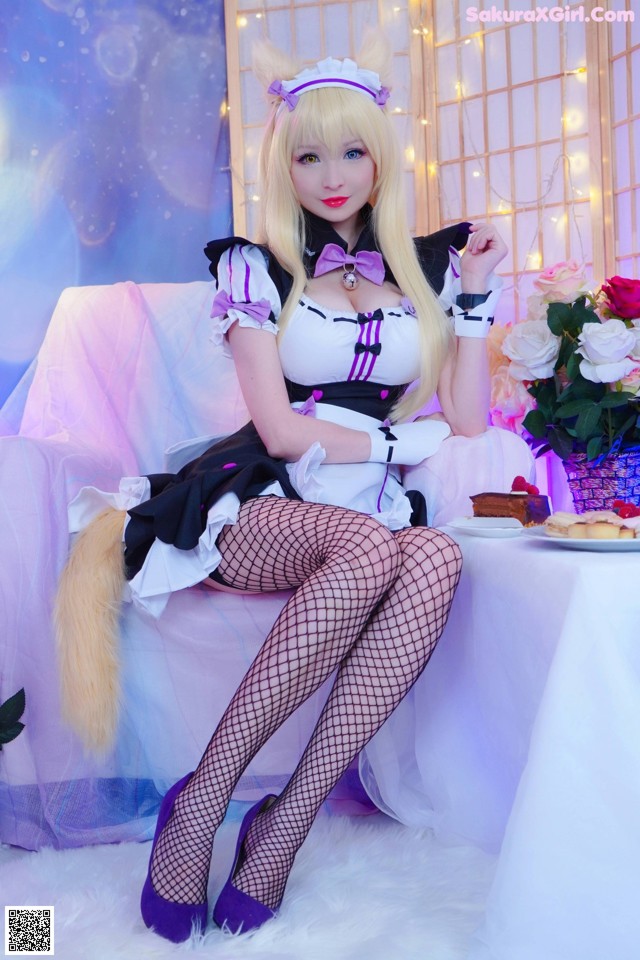 A woman in a maid outfit sitting on a white couch.