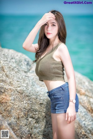 A woman sitting on a rock in the water.