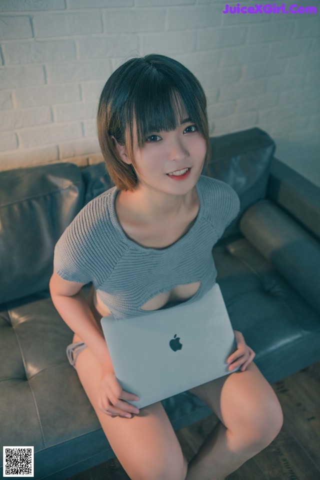 A woman sitting on a couch holding a laptop computer.