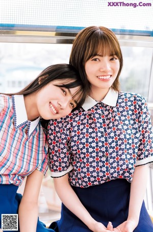 A couple of women sitting next to each other on a blue bench.