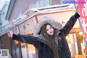A woman in a green bodysuit posing in the snow.