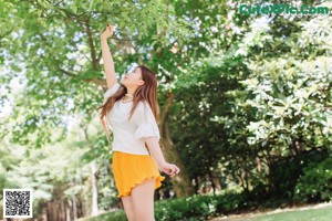 A woman in a white shirt and yellow skirt posing for a picture.