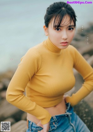 A woman in a yellow bikini sitting on a wooden bench.