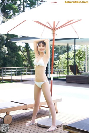 A woman in a white bikini standing next to a pool.