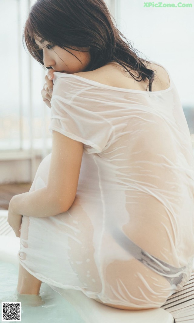 A woman in a white dress sitting in a bathtub.