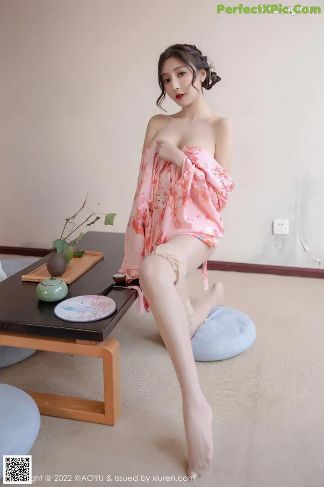 A woman in a pink dress sitting on a table.
