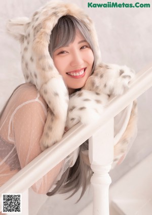 A naked woman sitting on a white couch wearing a furry hat.