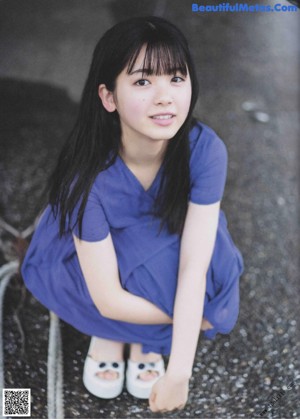 A young woman with long black hair and a blue dress.