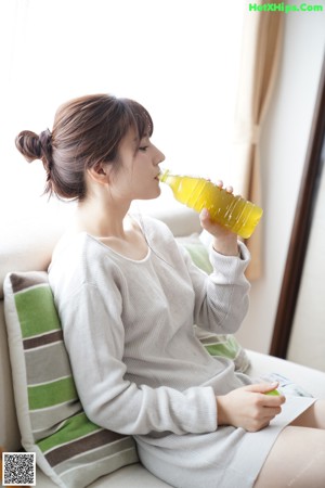 A woman sitting on a couch holding a bag of chips.