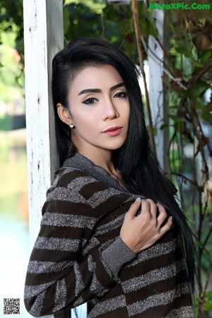 A naked asian woman posing on a balcony railing.