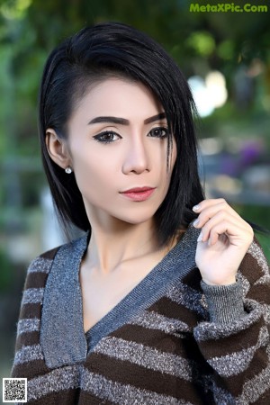 A woman in a black dress sitting on a bench.