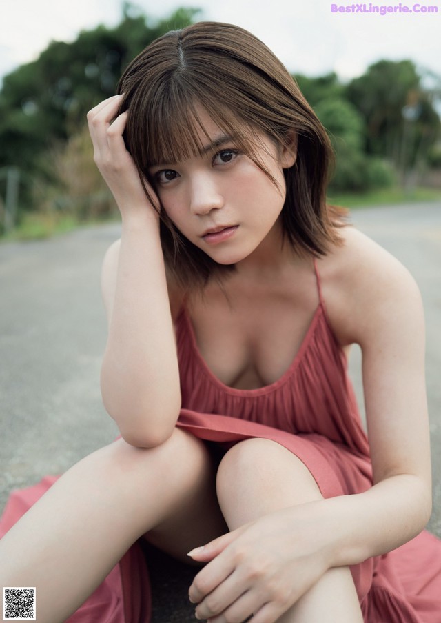 A woman in a pink dress sitting on the ground.