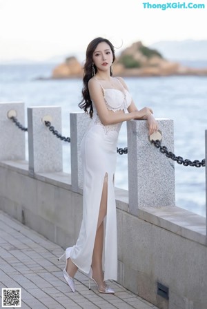 A woman in a white dress standing on a bridge.