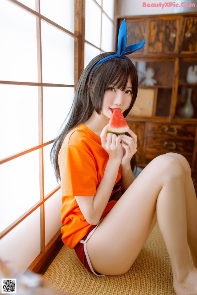 A woman sitting on the floor eating a slice of watermelon.