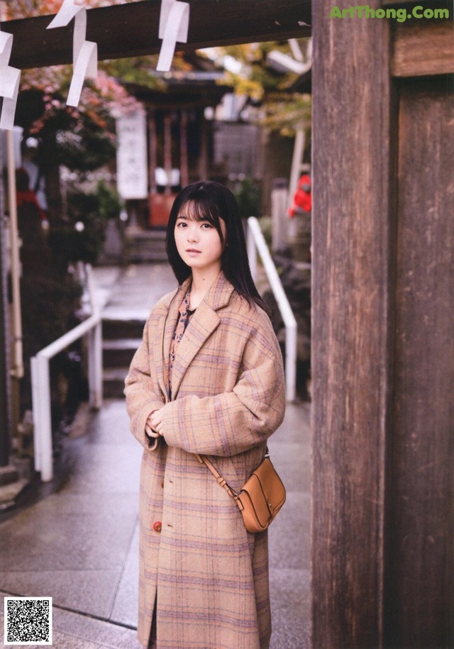 A woman standing in front of a wooden archway.