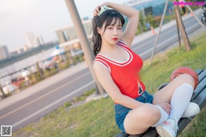 A woman in a red shirt and blue shorts holding a basketball.