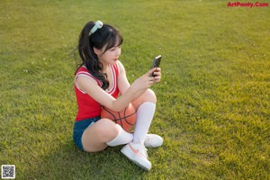 A woman in a red shirt and blue shorts holding a basketball.