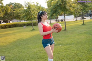 A woman sitting on the grass holding a basketball.