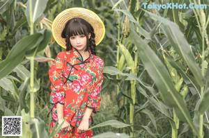 A woman in a straw hat standing in a field of tall grass.