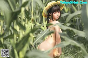 A naked asian woman holding a squash in a field.