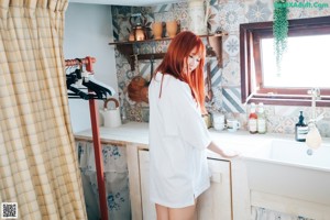 A woman in a white shirt is bending over on the floor.