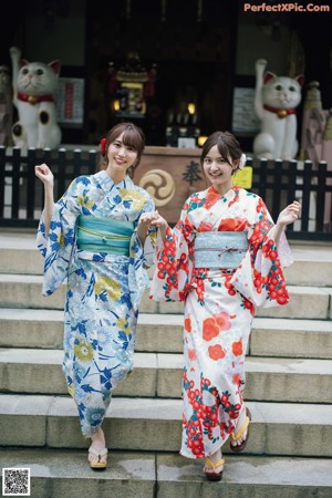 Two women in kimonos are walking down some steps.