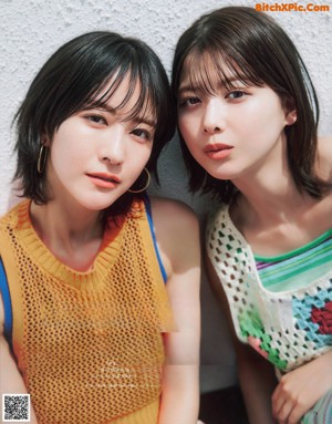 A couple of young women laying on top of a bed.