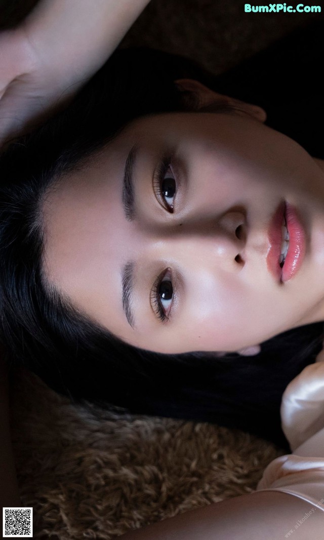 A woman laying on the floor with her hands on her head.