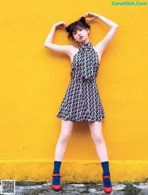 A woman sitting on the ground in front of a checkered wall.