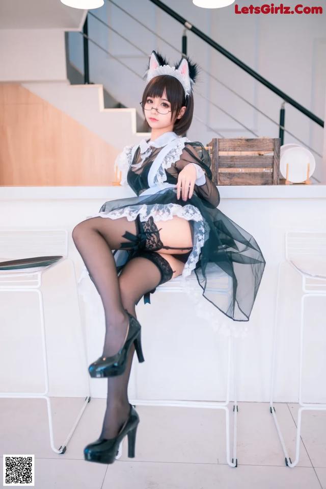 A woman in a black and white dress sitting on a white chair.