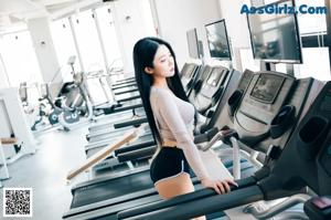 A woman in a black bikini standing on a treadmills.