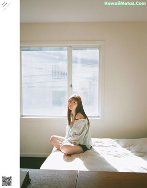 A woman sitting on a bed talking on a cell phone.