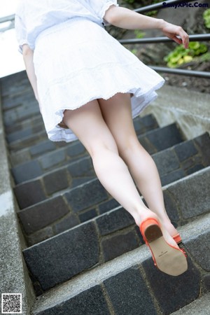 A woman in a white dress leaning on a railing.