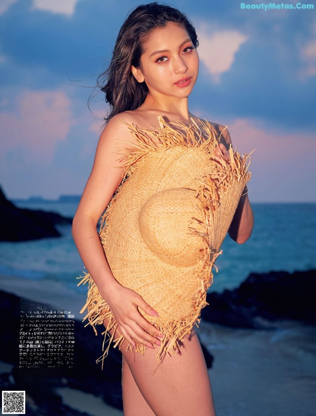 A woman in a straw hat standing on a beach.