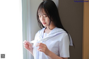 A woman in a white shirt and white panties sitting on the floor.