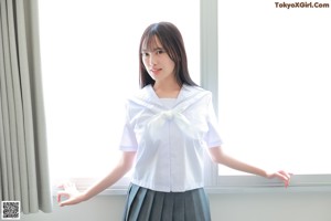 A woman in a school uniform sitting on the floor.