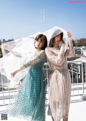 Two young women standing next to each other in front of a window.