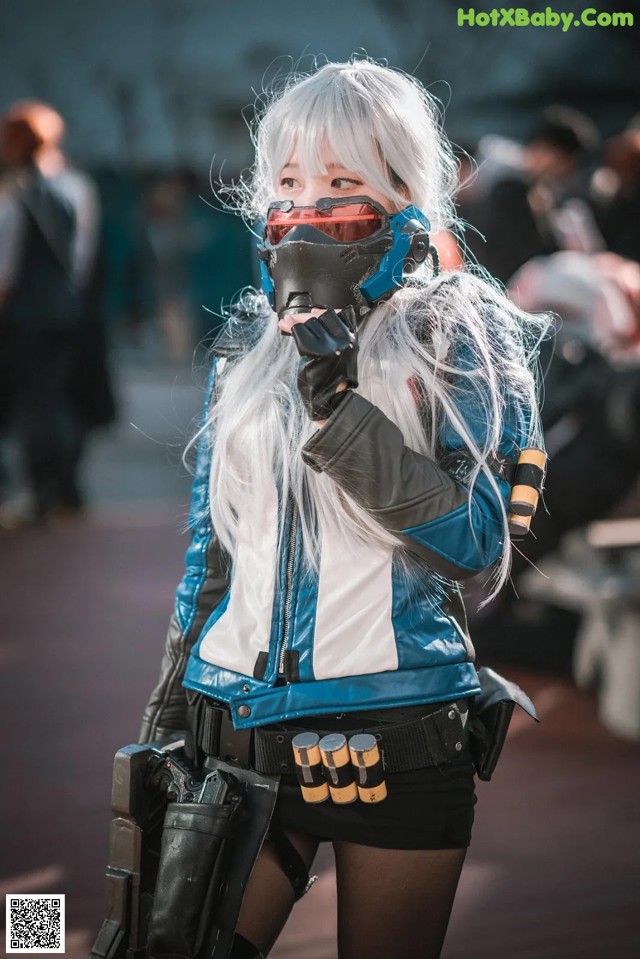 A woman in a blue and white outfit holding a gun.