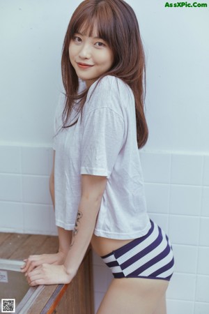 A woman in a white shirt and blue and white striped panties.