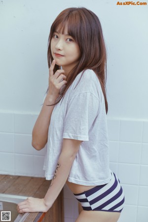 A woman in a white shirt and blue and white striped panties.